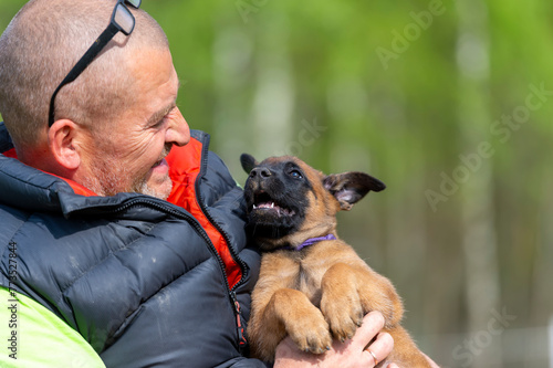 A man holds a Belgian Shepherd Malinois puppy in his arms