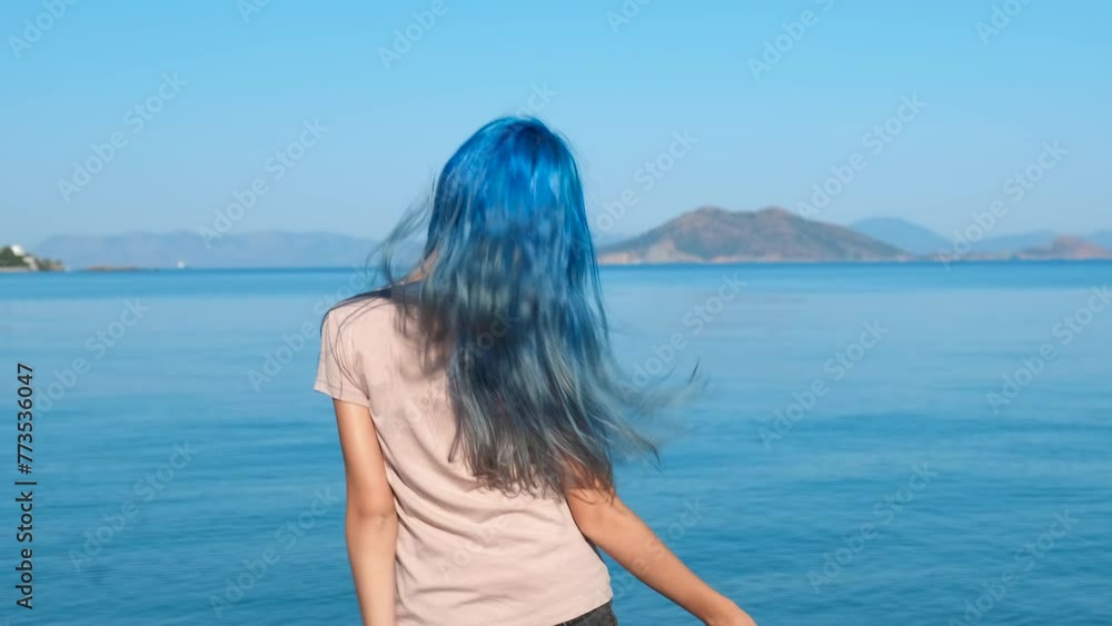 Blue teen enjoy dancing by sea. A playful stylish teen girl dancing on the empty shore by the blue sea waves during summer holidays. Blue teen enjoy dancing by sea. A playful stylish teen girl dancing on the empty shore by the blue sea waves during summer holidays.