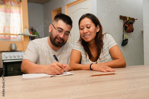 Happy young married couple sitting at home calculating household expenses. couple doing their accounts in the living room at home - Hispanic couple at home