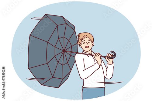 Man with umbrella turned backwards walks down street during severe life-threatening storm. Pedestrian in casual clothes caught in hurricane walking around city and needs shelter