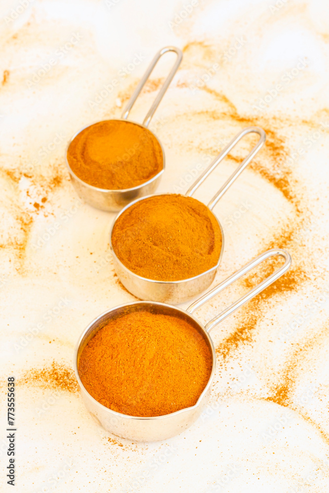Fototapeta premium Natural cinnamon powder in metal bowls on white surface
