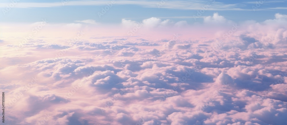 Fluffy white clouds floating in a clear blue sky above a vibrant pink and blue horizon