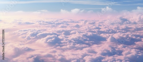 Fluffy white clouds floating in a clear blue sky above a vibrant pink and blue horizon