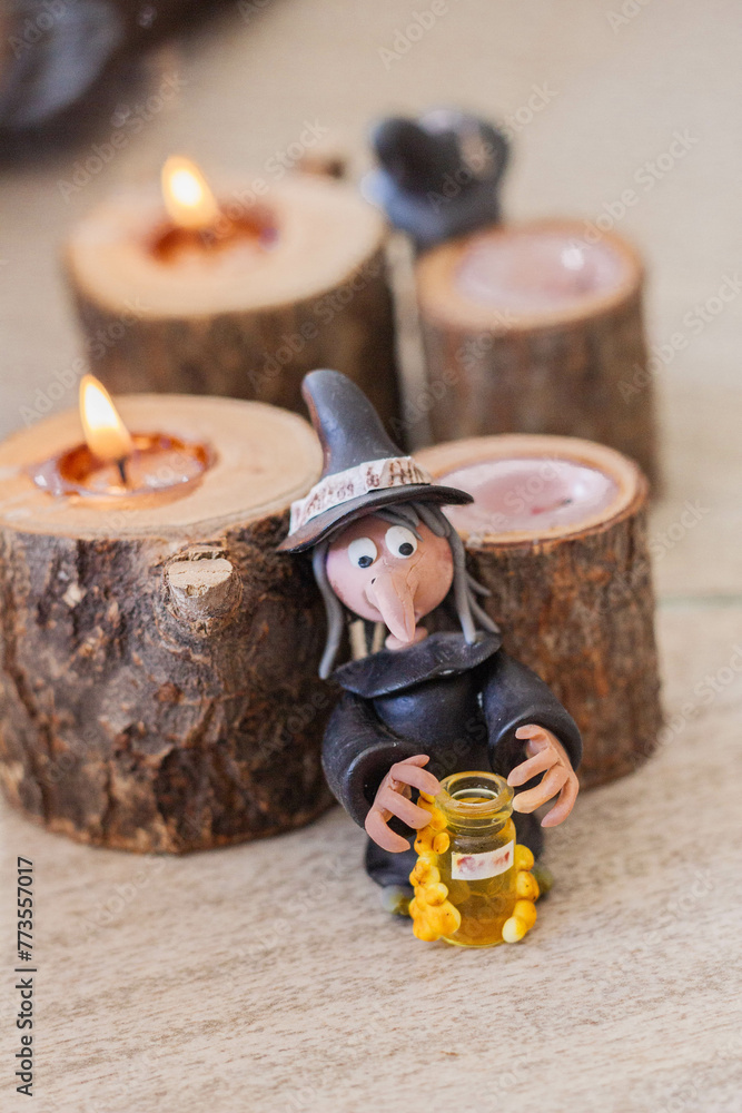 Fototapeta premium Witch figurine with bottle of potion and candle on the table