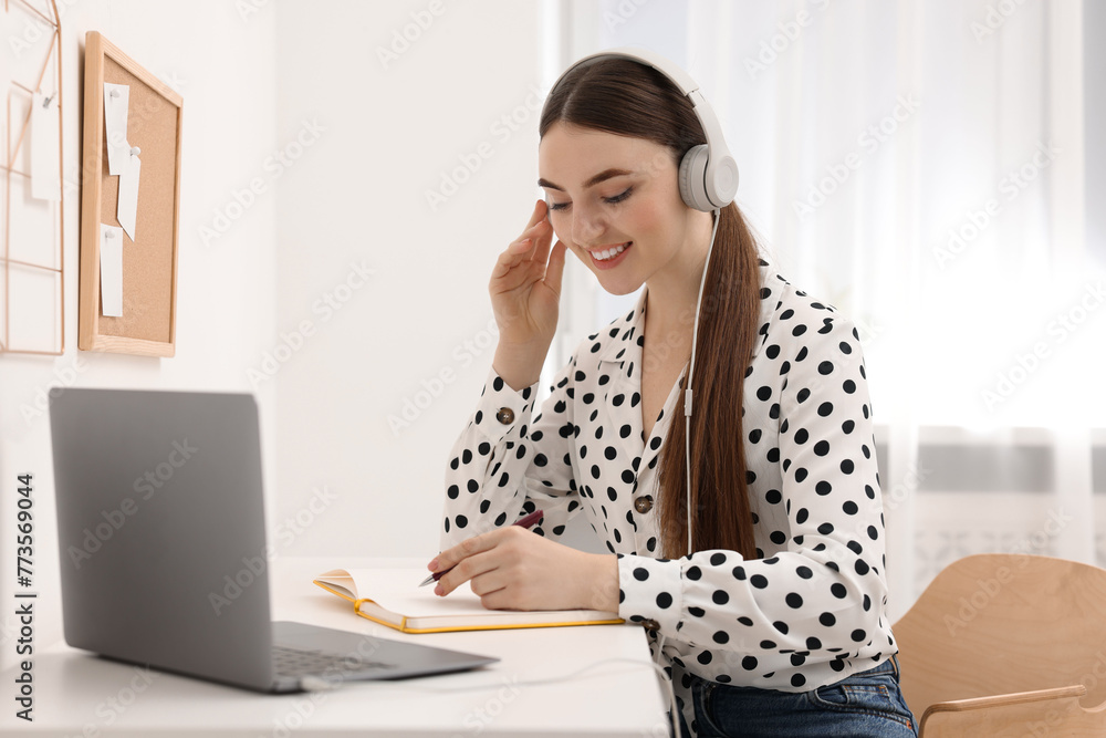 E-learning. Young woman using laptop during online lesson at table indoors E-learning. Young woman using laptop during online lesson at table indoors