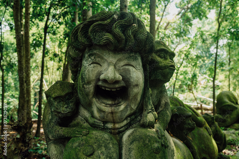 Stone sculpture of happy face and monkeys in Monkey Forest. Ubud, Bali, Indonesia.