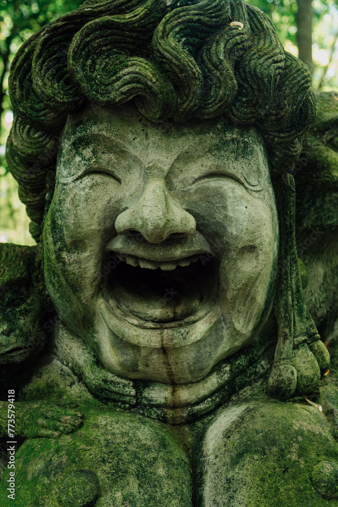 Stone sculpture of happy face and monkeys in Monkey Forest. Ubud, Bali, Indonesia.