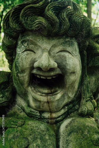 Stone sculpture of happy face and monkeys in Monkey Forest. Ubud, Bali, Indonesia. © Zenstratus