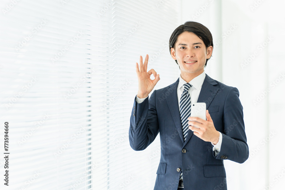スマホを持ってOKサインを出す若いアジア人男性ビジネスマン
スマホを持ってOKサインを出す若いアジア人男性ビジネスマン