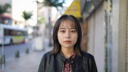 Slow-motion video of the face of an Okinawan woman in her 20s in winter clothes on Kokusai Street in Naha City, Okinawa Prefecture 沖縄県那覇市の国際通りの冬服の20代の沖縄県民女性の顔のアップのスローモーション映像 photo