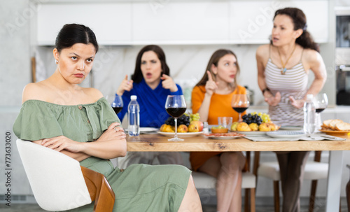 Friends quarrel at a party. Upset woman listens to screams and indignation of her girlfriends