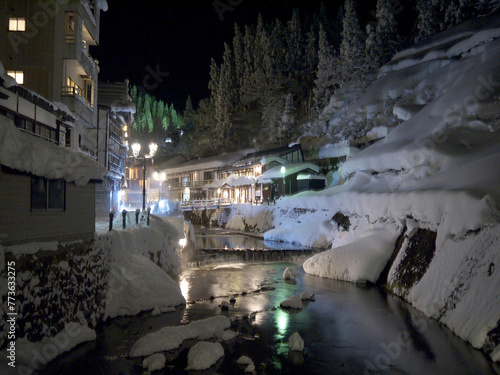 Idyllic Japanese small village new year night winter scenery with traditional houses and wooden bridge with lantern over the river, Ginzan onsen hot spring, Yamagata, Japan photo
