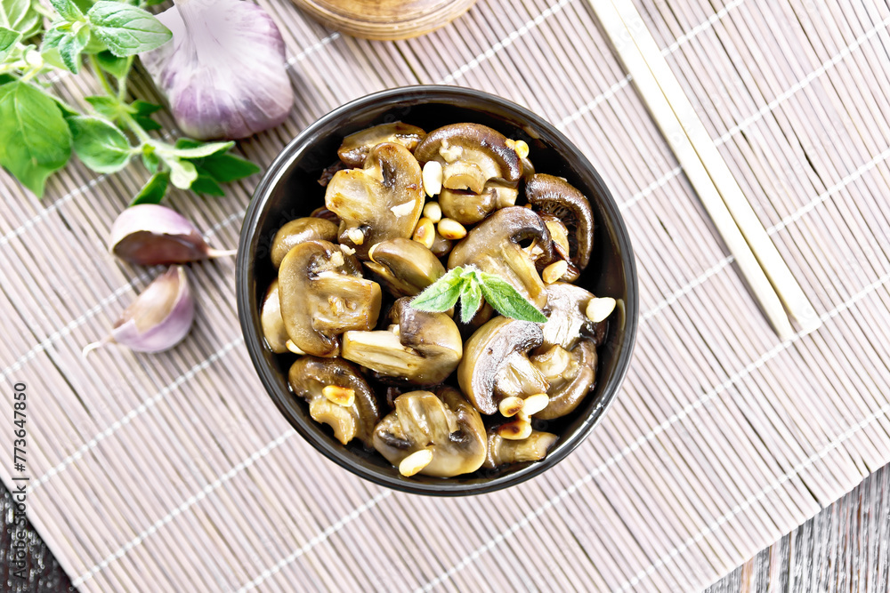Champignons with oregano and nuts in bowl on bamboo napkin top Champignons with oregano and nuts in bowl on bamboo napkin top