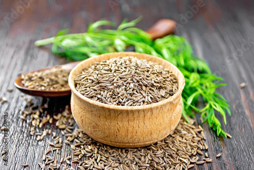 Cumin seeds in bowl and spoon with herbs on board