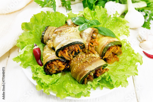 Rolls of zucchini with carrots in plate on board