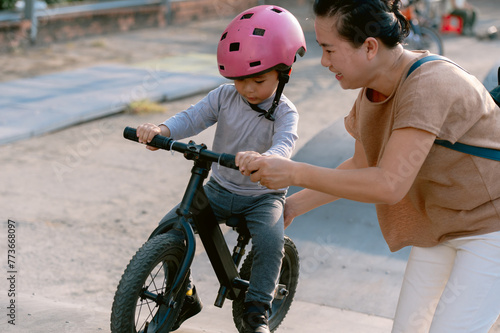 Asian mother and child pratice bike on the playground photo