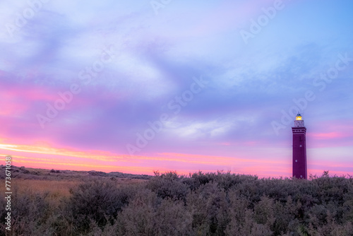 The image captures a picturesque scene where nature and human creation meet harmoniously. A tall, slender lighthouse stands out against the captivating backdrop of a twilight sky. The lighthouse