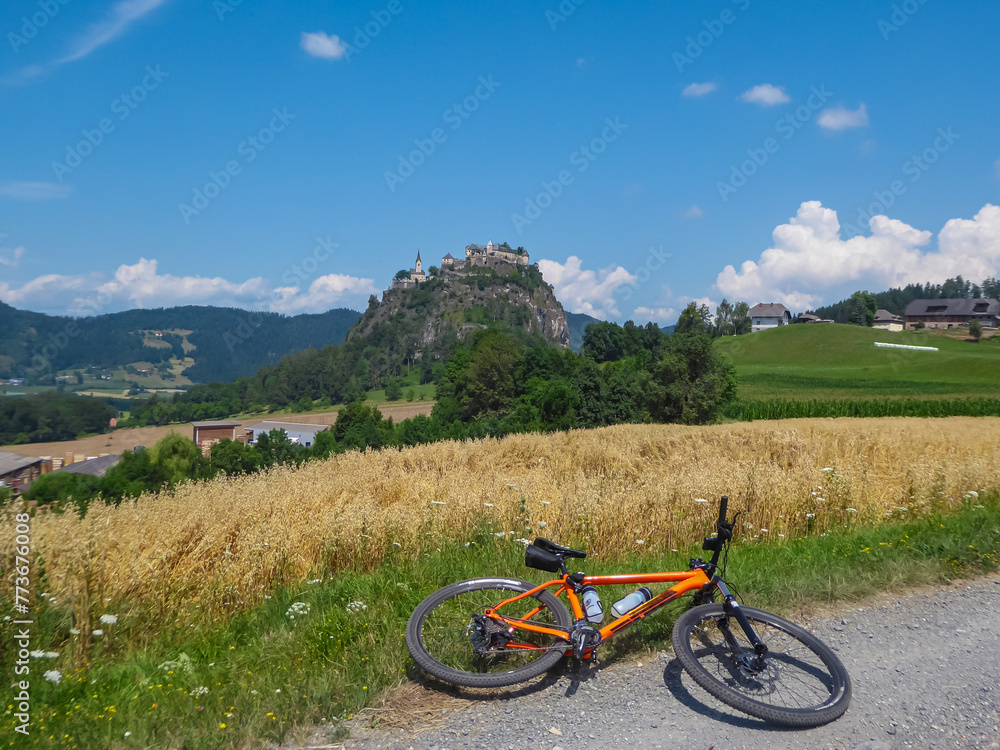 Mountain bike on scenic road leading to medieval castle Burg Hochosterwitz build on hilltop in Sankt Georgen am Längsee, Sankt Veit an der Glan, Carinthia, Austria. Hill surrounded by vast forest