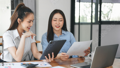 Young women working together, using laptop and graph chart, office interior