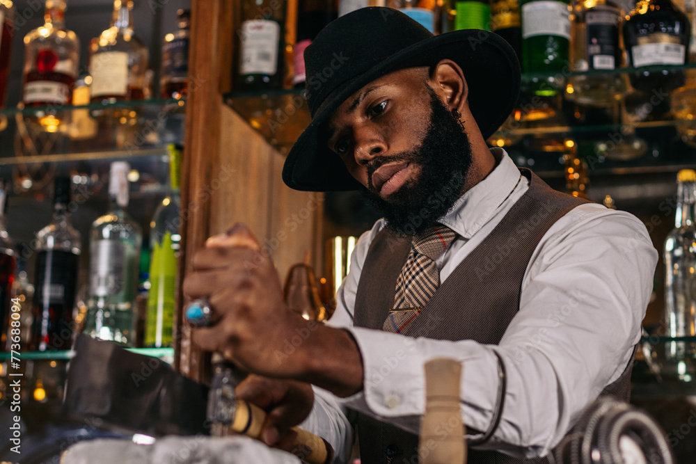 Close-up of a black bartender cutting a large ice cube to prepare a cocktail Close-up of a black bartender cutting a large ice cube to prepare a cocktail