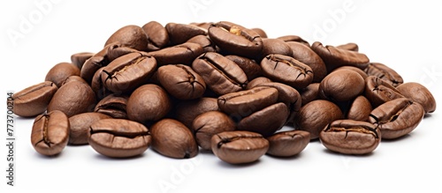A heap of aromatic coffee beans spread out in a pile on a plain white background for a clean and simple composition