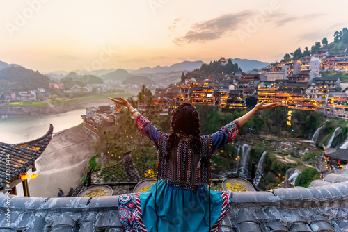 Young female tourist in traditional dress looking at the beautiful landscape at the Furong old Town, The famous tourist destination at Hunan Province, China © Kittiphan
