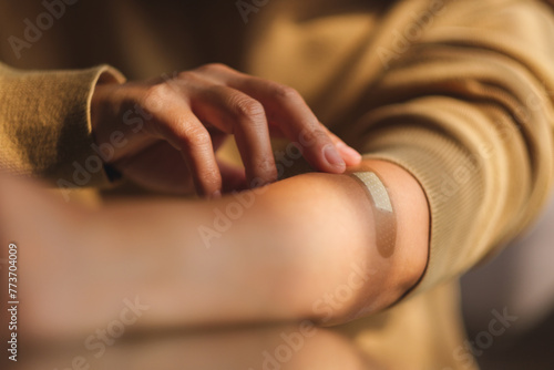 Closeup image of a young woman with a band aid, medical plaster, adhesive bandage on her arm