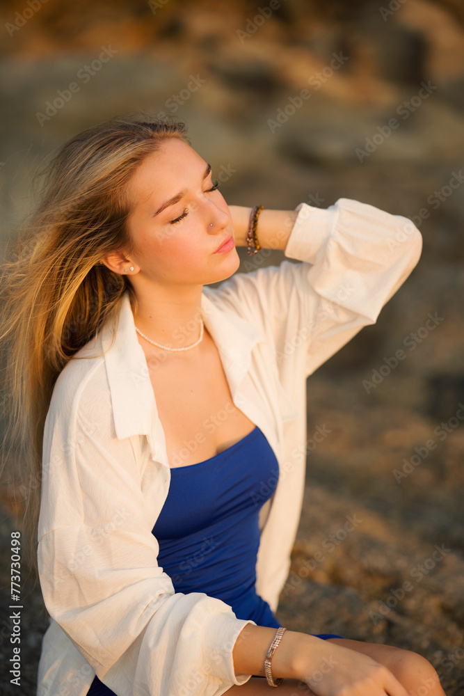 Young beautiful teenager girl with long hair european model posing on the sunset beach