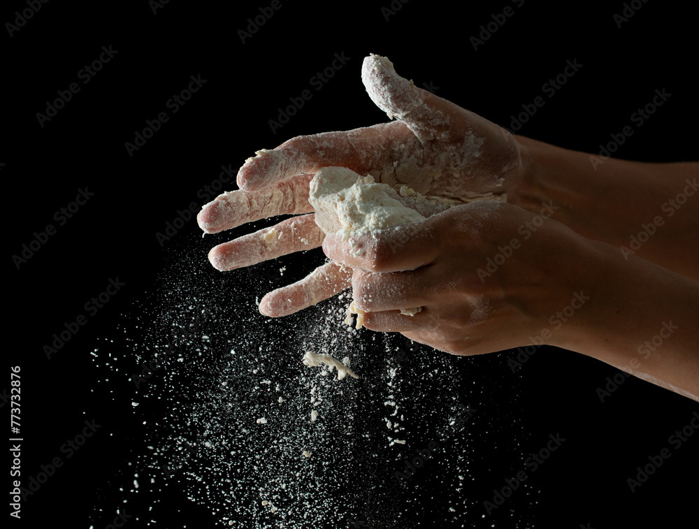 Фотография hands knead dough on a black background.