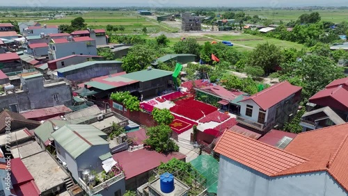 Aerial drone video of village in Vietnam with bundles of red incense outside drying in a courtyard between buildings  photo