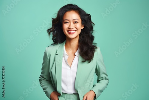 A successful East Asian businesswoman in her late 30s, against a gentle mint green background, flashing a radiant smile © Hanna Haradzetska