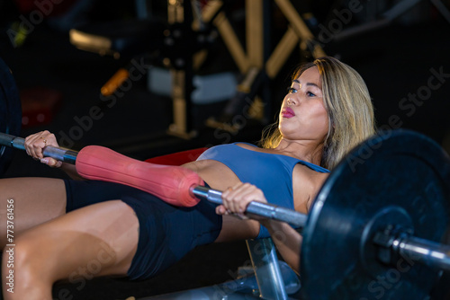 Asian woman is practice weight lifting on barbell for core muscle inside gym with dark background for exercising and workout concept