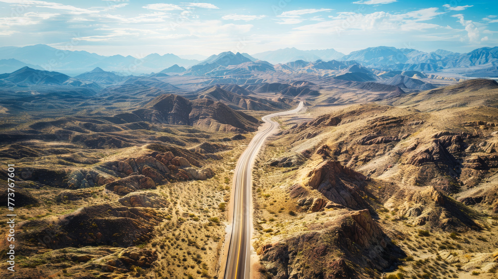 Aerial view of a highway passing through mountains, canyons and arid landscapes