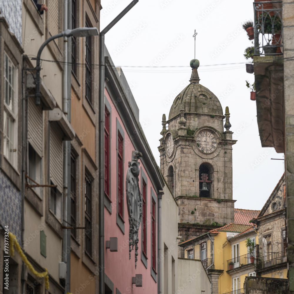An old, stone clock tower, seen amoungst the old city streets of Porto, Portugal