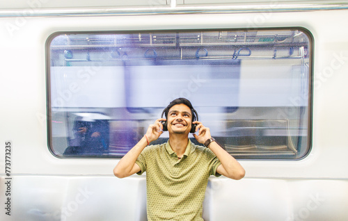 Portrait of young Indian man passenger traveling and using his smartphone in the metro or subway train. Metro and Public transportation concept. Bengaluru, India.