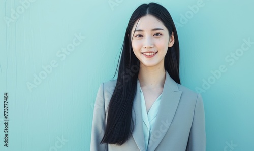 Portrait of a Japanese young business woman wearing a suit working in the office on a blue background
