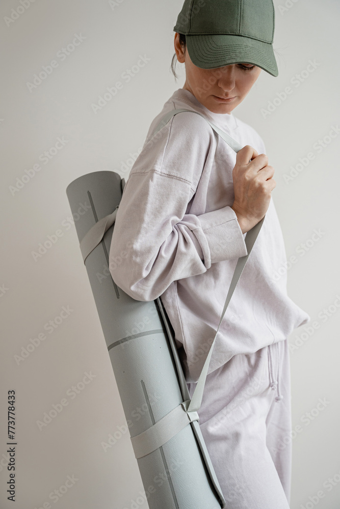 Woman in pastel purple sportswear with yoga mat outfit posing over white wall. Fitness, workout, sport fashion background - obrazy, fototapety, plakaty 