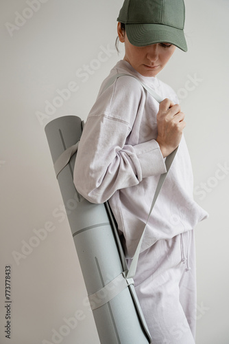 Woman in pastel purple sportswear with yoga mat outfit posing over white wall. Fitness, workout, sport fashion background