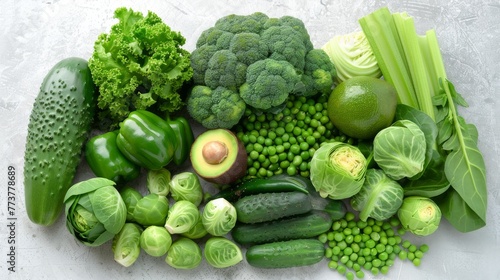 Fresh green vegetables variety on a rustic white background from overhead, broccoli, celery, avocado, brussels sprouts, kiwi, peppers, peas, beans, lettuce
