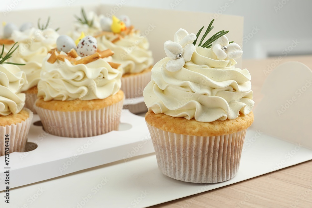 Tasty Easter cupcakes in box on wooden table, closeup Tasty Easter cupcakes in box on wooden table, closeup