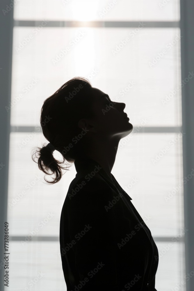 A woman is standing in front of a window with her head tilted
