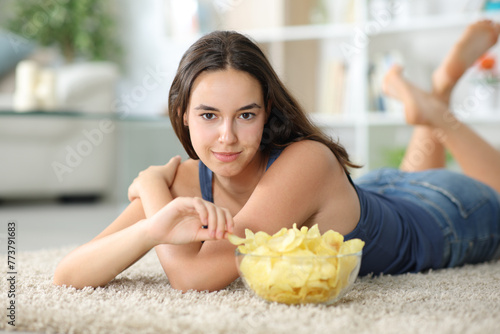Beautiful woman looks at you eating potato chips