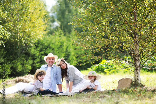 Happy family with children having picnic in park, parents with kids sitting on garden grass and eating watermelon outdoors