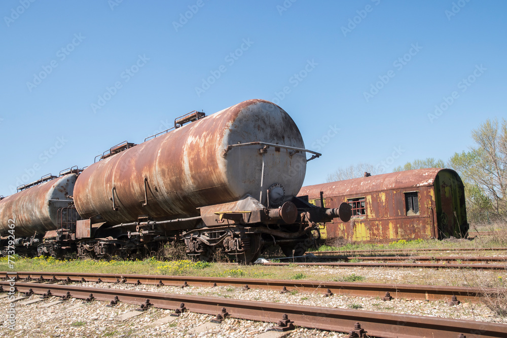 Old rusty abandoned railway oil tankers in the middle of a field on sunny day Old rusty abandoned railway oil tankers in the middle of a field on sunny day