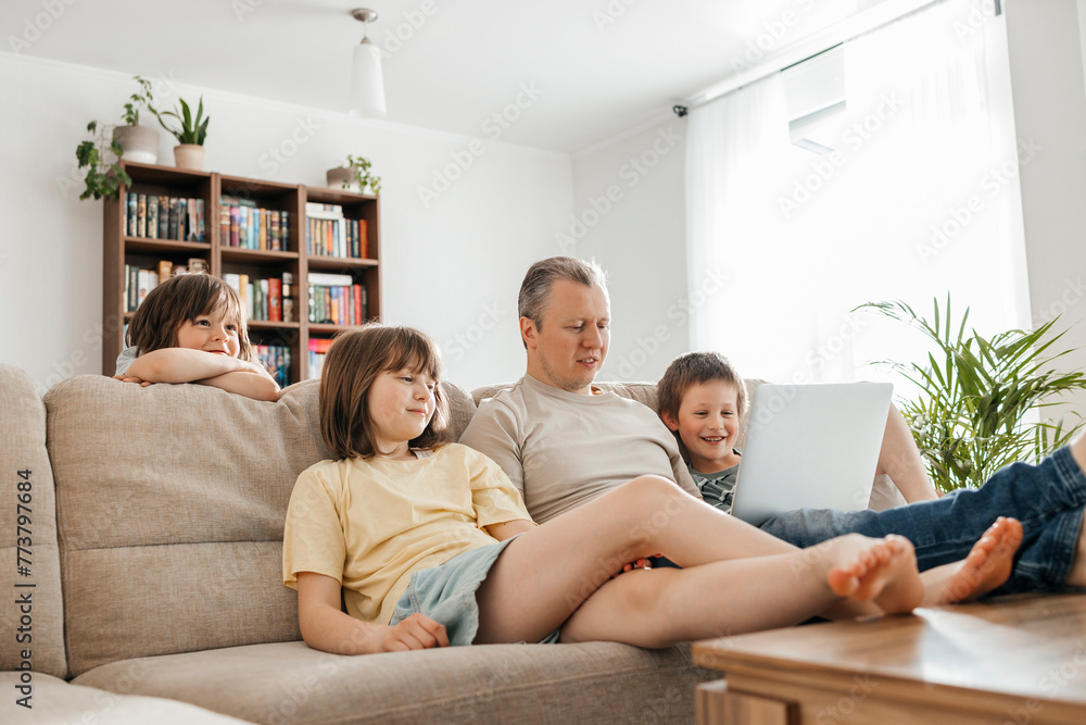 Father watching movie with children on laptop at home Father watching movie with children on laptop at home