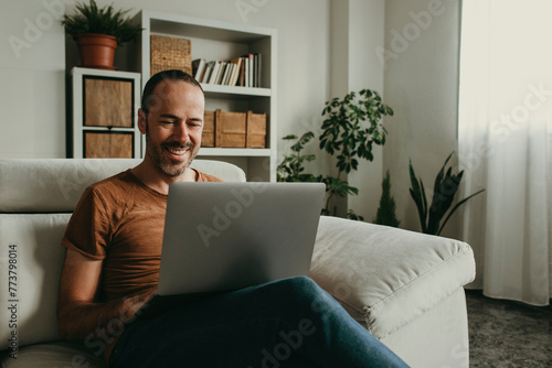 Happy man watching movie on laptop at home photo