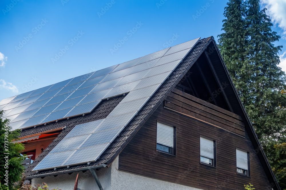 Solar panels on rooftop of house under blue sky in Bavaria, Germany Solar panels on rooftop of house under blue sky in Bavaria, Germany