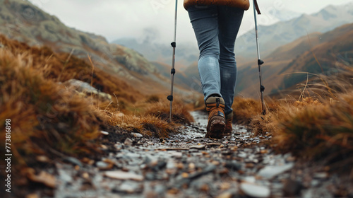 focus on shoes of cropping, people hiker in the mountains.Woman hiker ascends with trekking poles, showcasing the strength and resilience of outdoor enthusiasts. photo