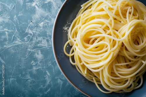 Plate of cooked spaghetti with parmesan cheese on textured background