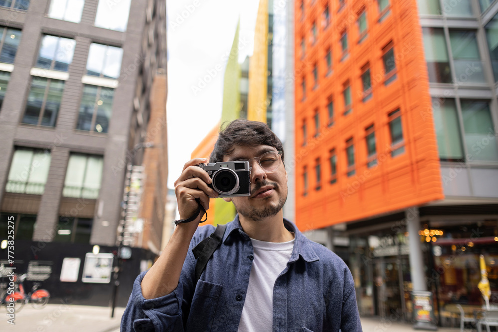Photographer man looking at camera between colorful buildings photographing with his camera Photographer man looking at camera between colorful buildings photographing with his camera